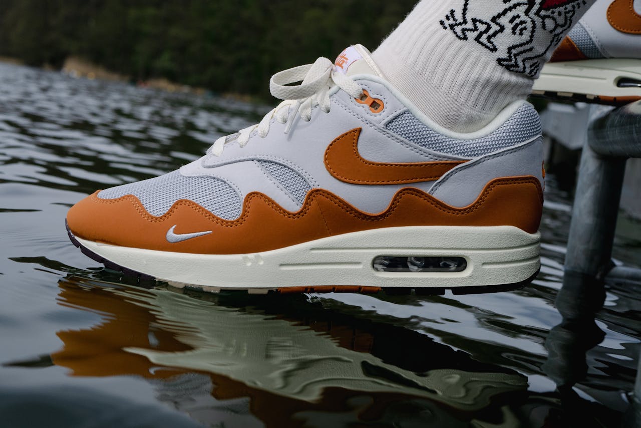 Close-up of a stylish Nike Air Max sneaker on a dock, reflecting in water, showcasing a fashionable and sporty look.