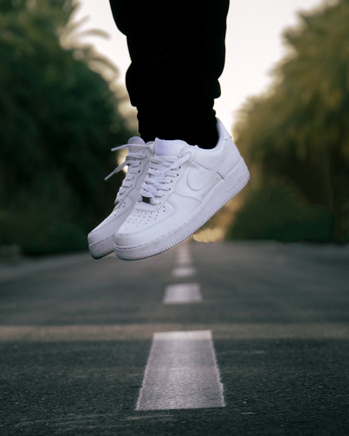White sneakers captured mid-air on a road in Ouargla, showcasing style and movement.