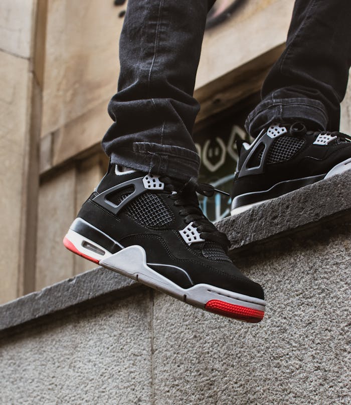 Stylish black sneakers on urban stone wall, perfect for streetwear fashion lovers.